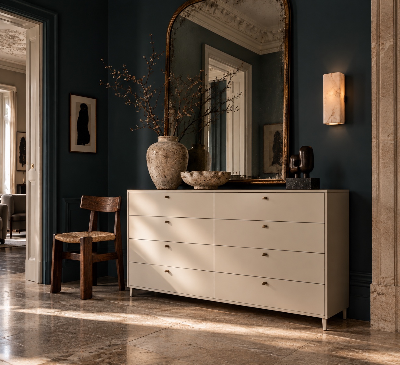 A basic chest of drawers placed beneath an antique mirror